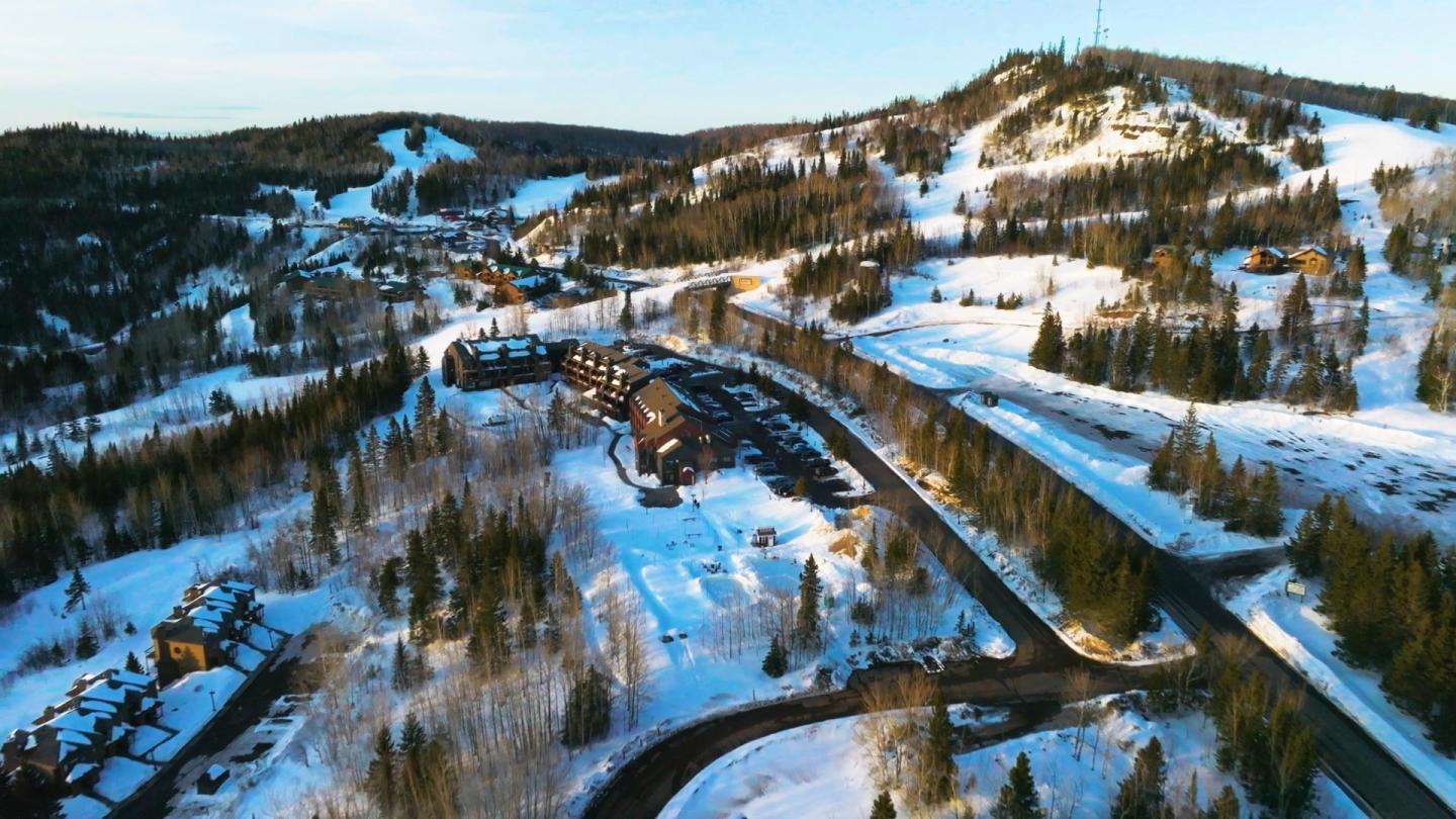 Snowy village and winding roads with forested hills in the background.
