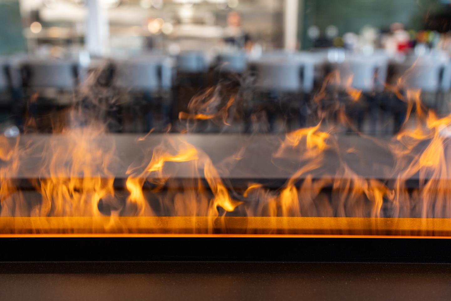 Flames flickering from a linear fireplace in a modern setting.