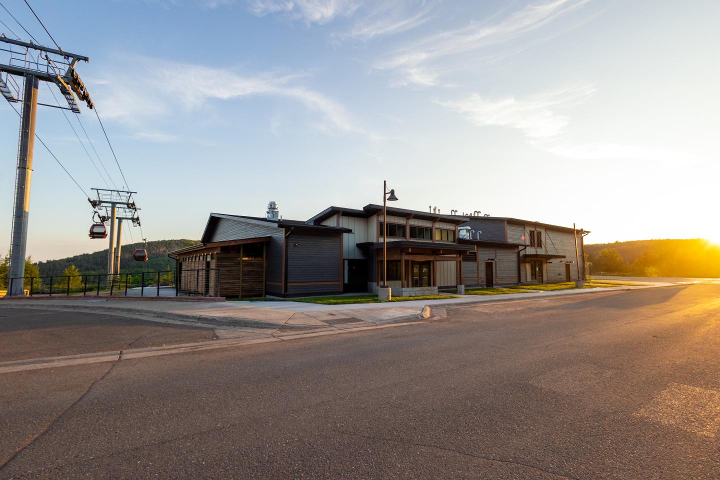 Rustic building at sunset, road and power lines in front.