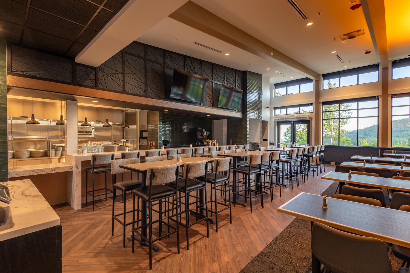 Modern restaurant interior with bar seating and large windows.