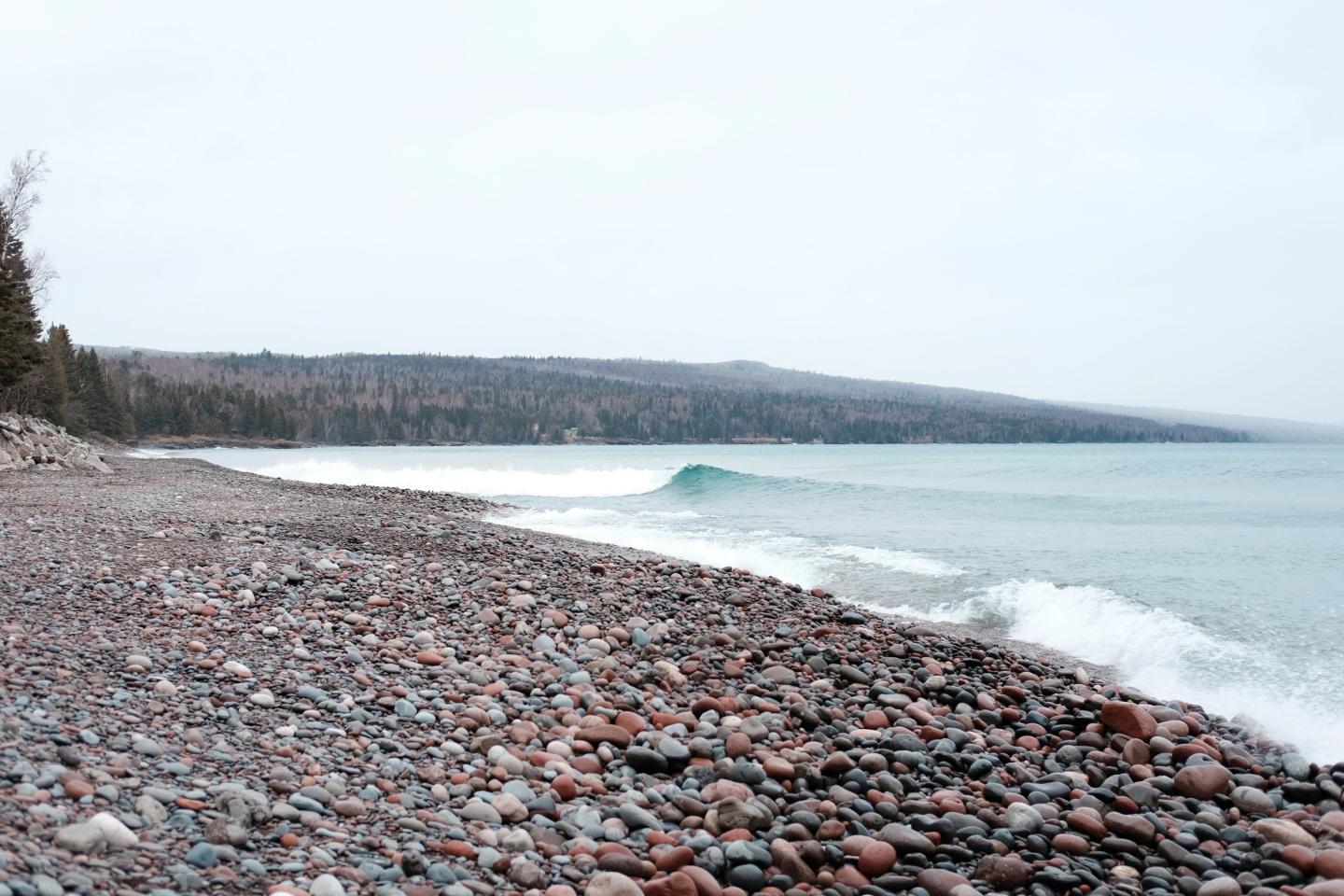 Rocky beach with gentle waves and overcast sky.