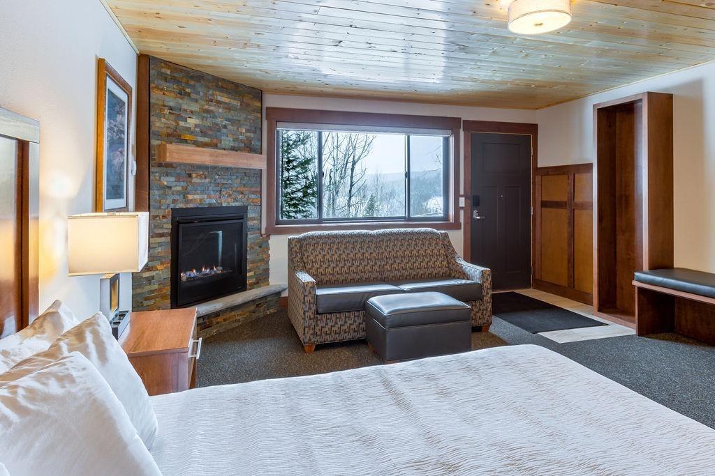 Cozy hotel room with stone fireplace, sofa, and large window.