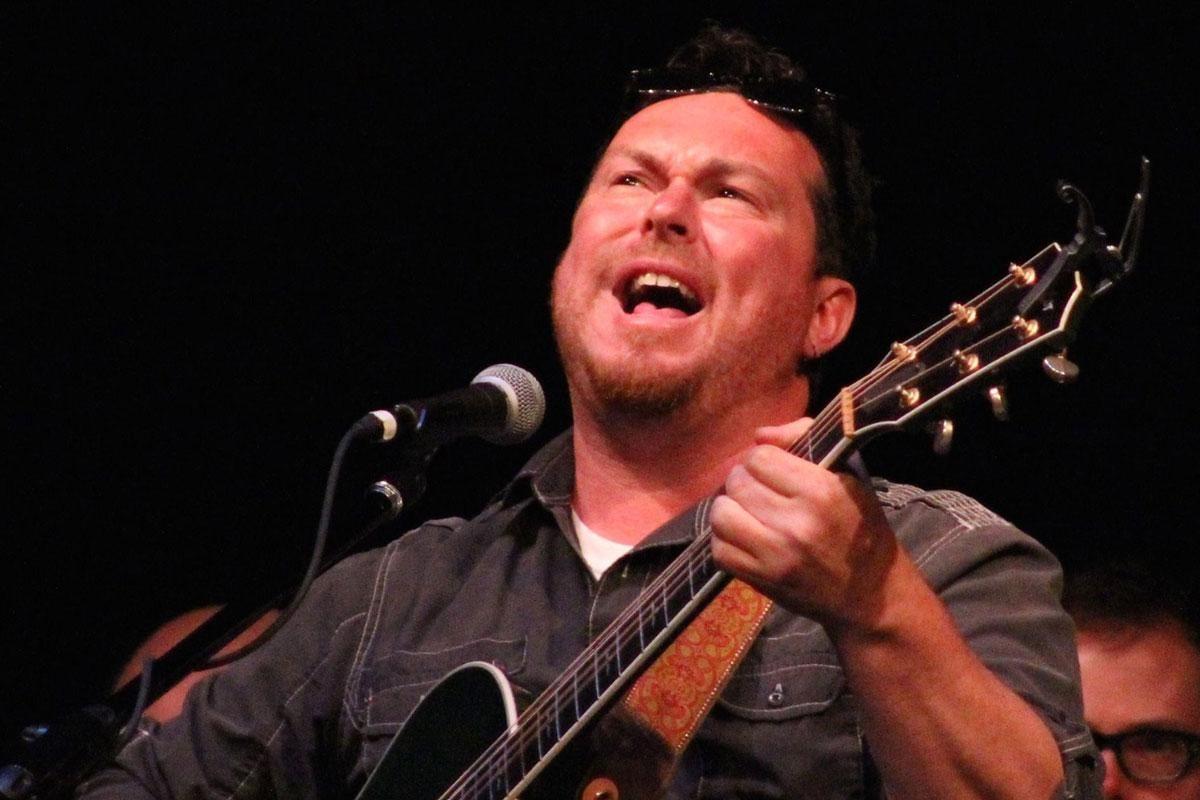 Singer passionately playing guitar on stage.