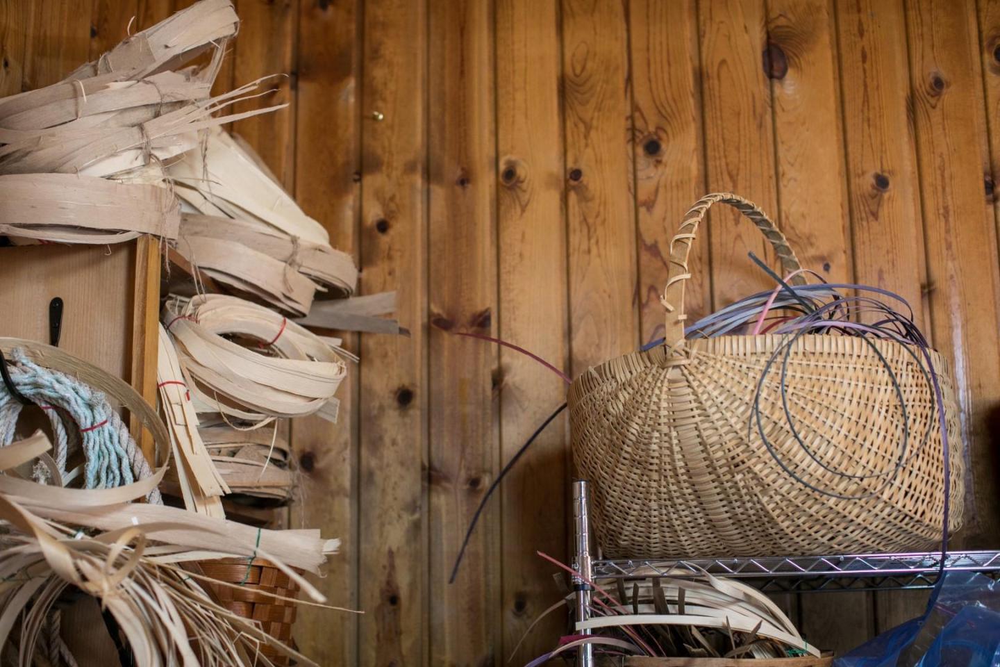 Basket weaving materials and tools against a wooden wall.
