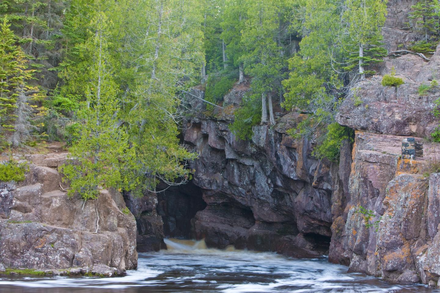 River flowing through a rocky gorge surrounded by lush green trees.