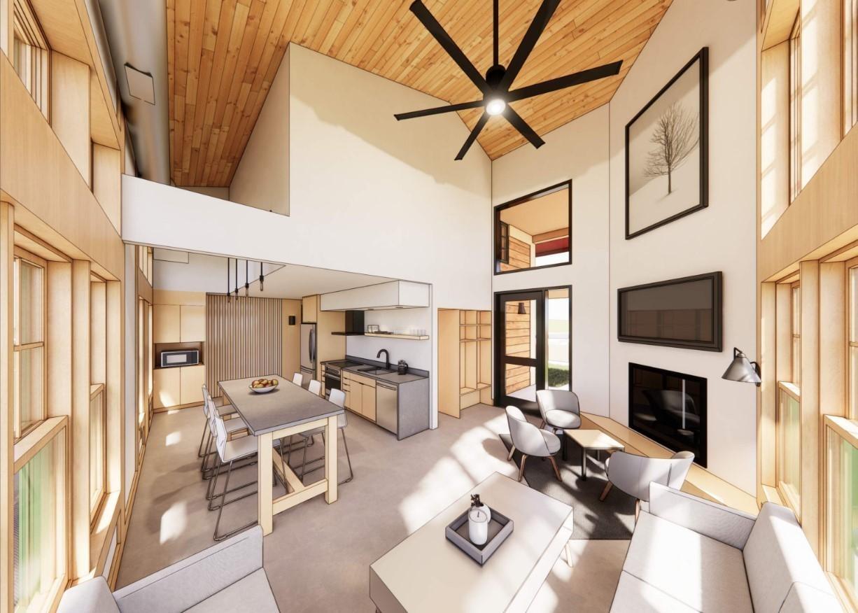 Modern living room with high ceiling, large fan, and open kitchen. Neutral tones and natural light.