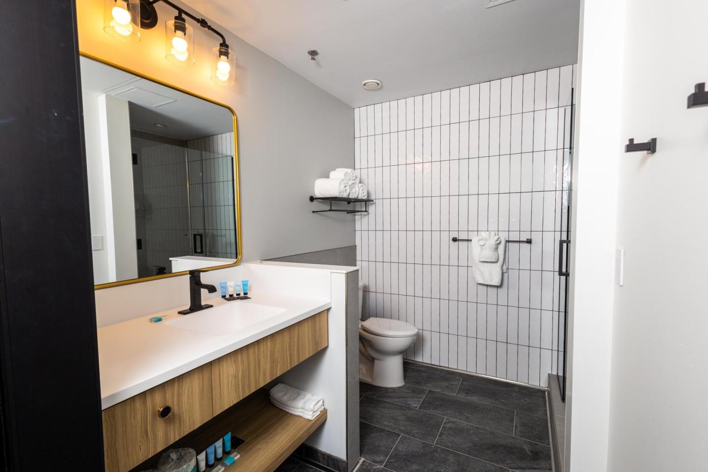Modern bathroom with large mirror, counter, and tiled wall.