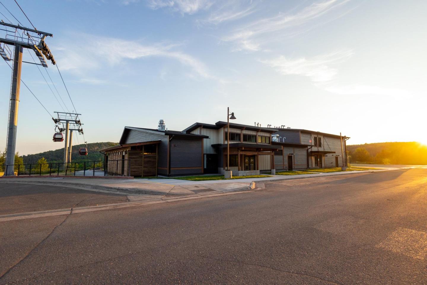 Sunlit building by an empty road with power lines, evening sky in the background.