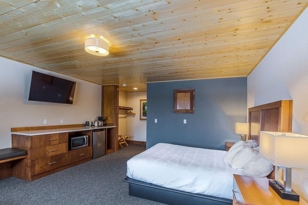 Cozy hotel room with a large bed, wooden ceiling, and wall-mounted TV.