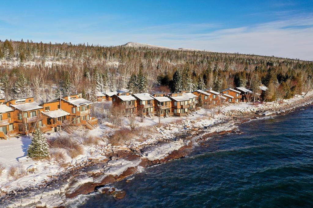 Snowy lakeside cabins with forest and mountains.