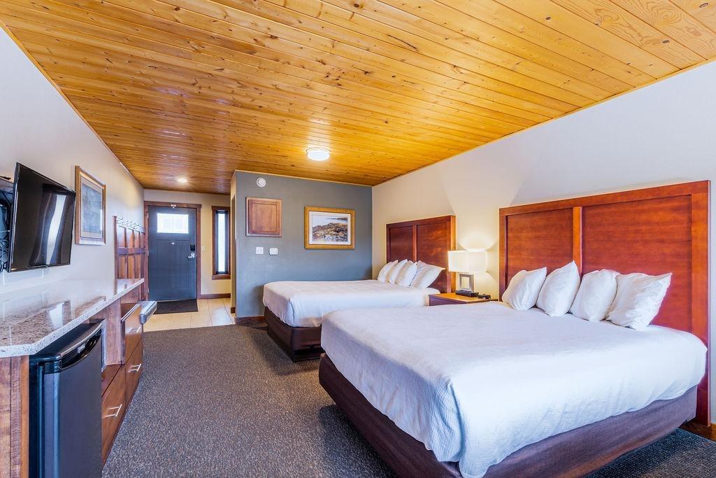 Hotel room with two beds, wooden accents, and a wall-mounted TV.