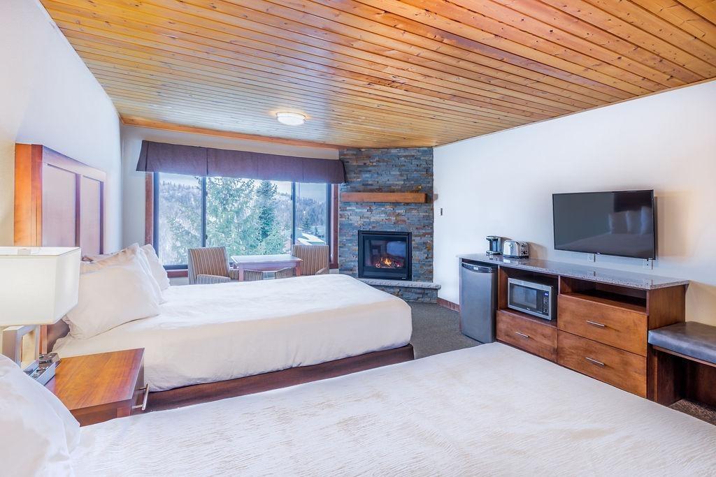 Cozy hotel room with two beds, a fireplace, TV, and mountain view.