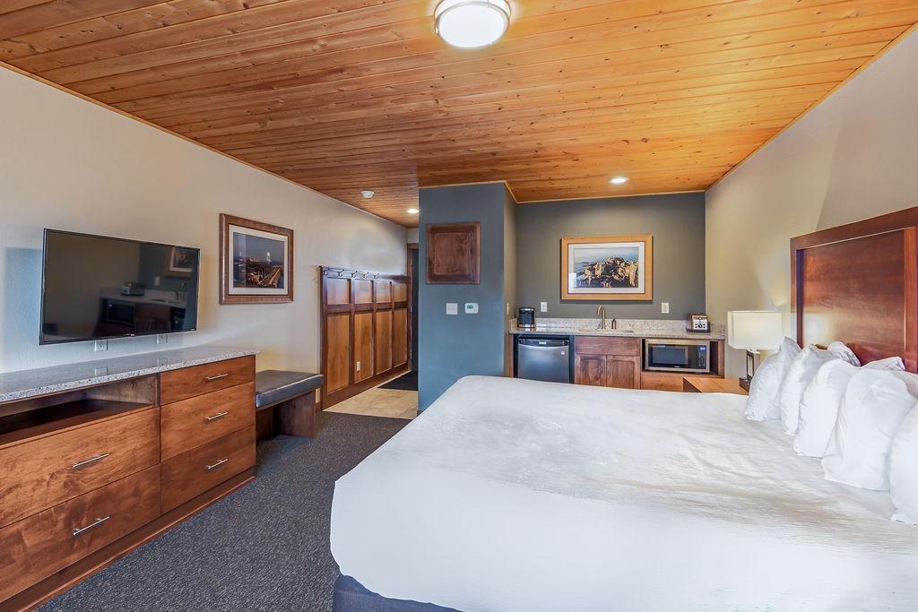 Cozy hotel room with a large bed, TV, and wood-paneled decor.