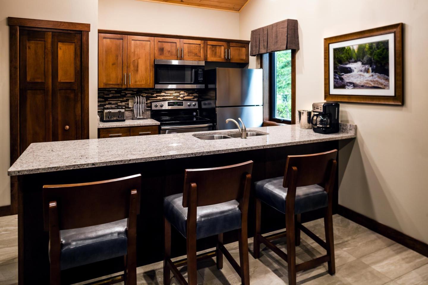 Cozy kitchen with wooden cabinets, granite island, and three chairs.