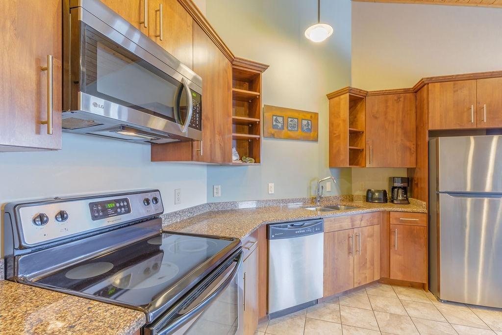 Kitchen with stainless steel appliances, wooden cabinets, and granite countertops.