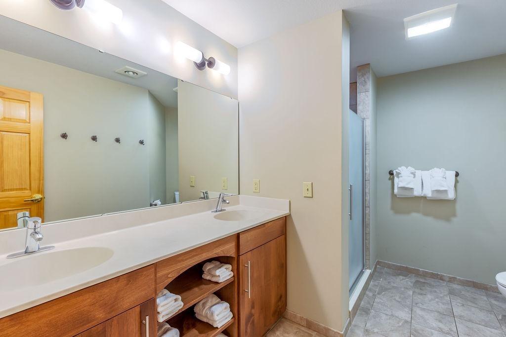 Bathroom with double sinks, large mirror, and a shower.