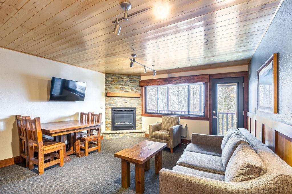 Cozy living room with sofa, fireplace, and large windows.