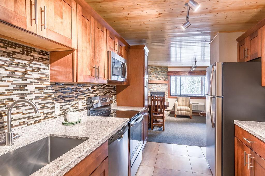 Modern kitchen with wooden cabinets, granite countertops, and stainless steel appliances.