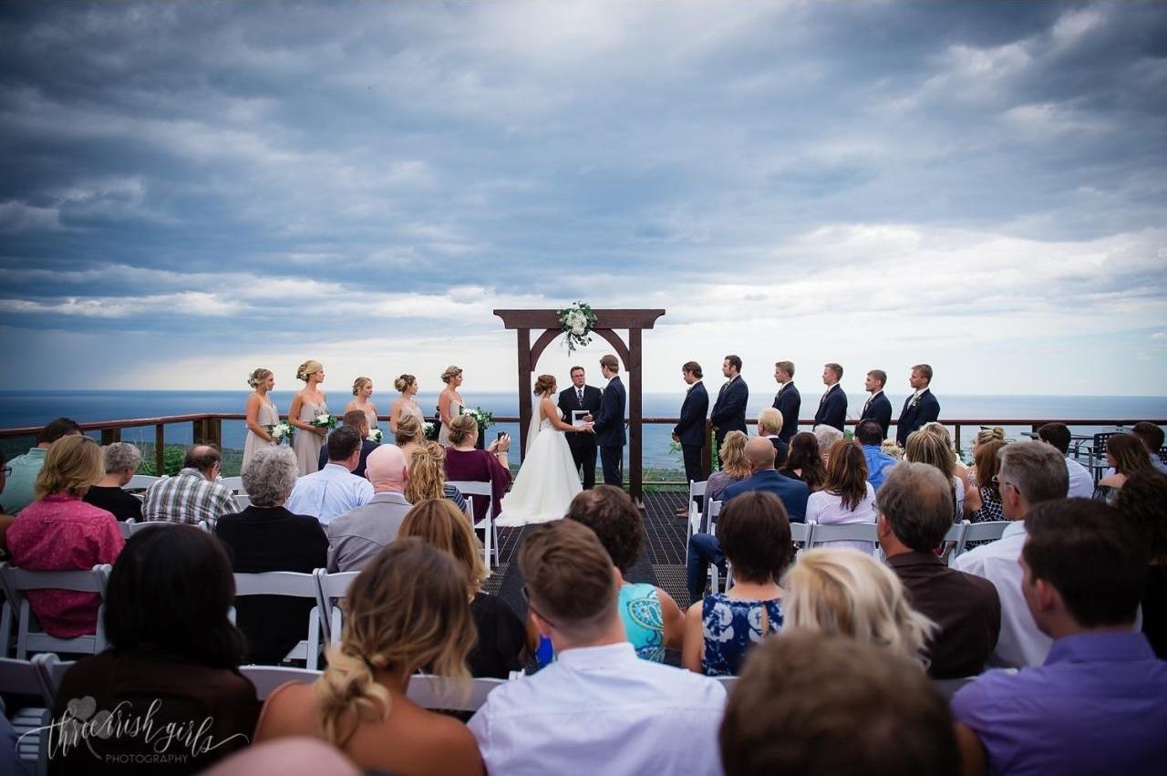 Outdoor wedding ceremony with guests seated and a cloudy sky.