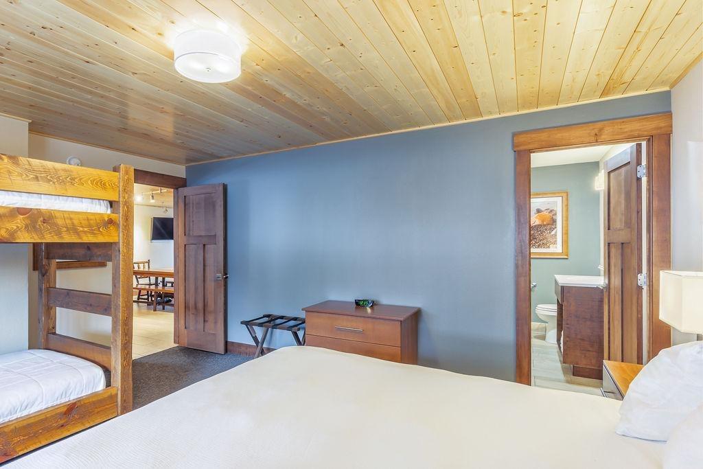 Cozy bedroom with bunk beds, wooden ceiling, and blue accent wall.
