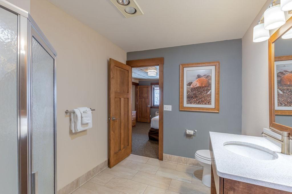 Bathroom with a shower, vanity, and towels, open door to bedroom.