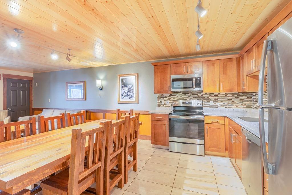 Cozy kitchen with wooden cabinets, table, and stainless steel appliances.