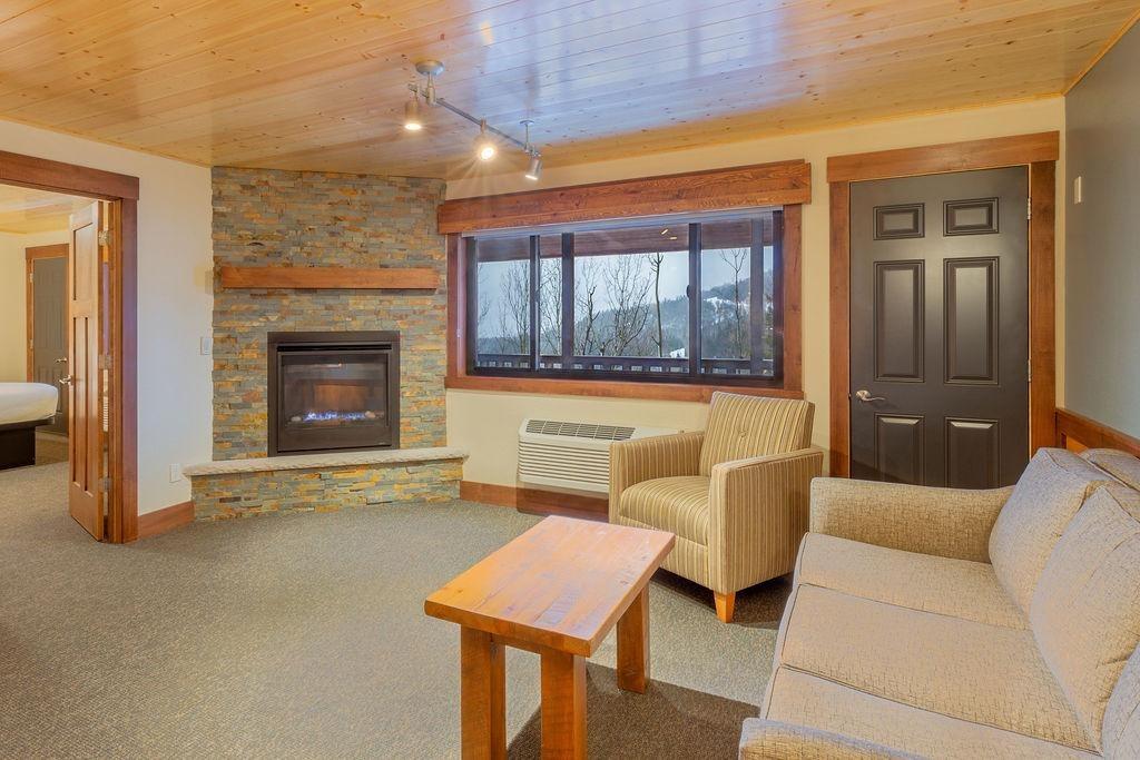 Cozy living room with fireplace, beige sofa, and large window.