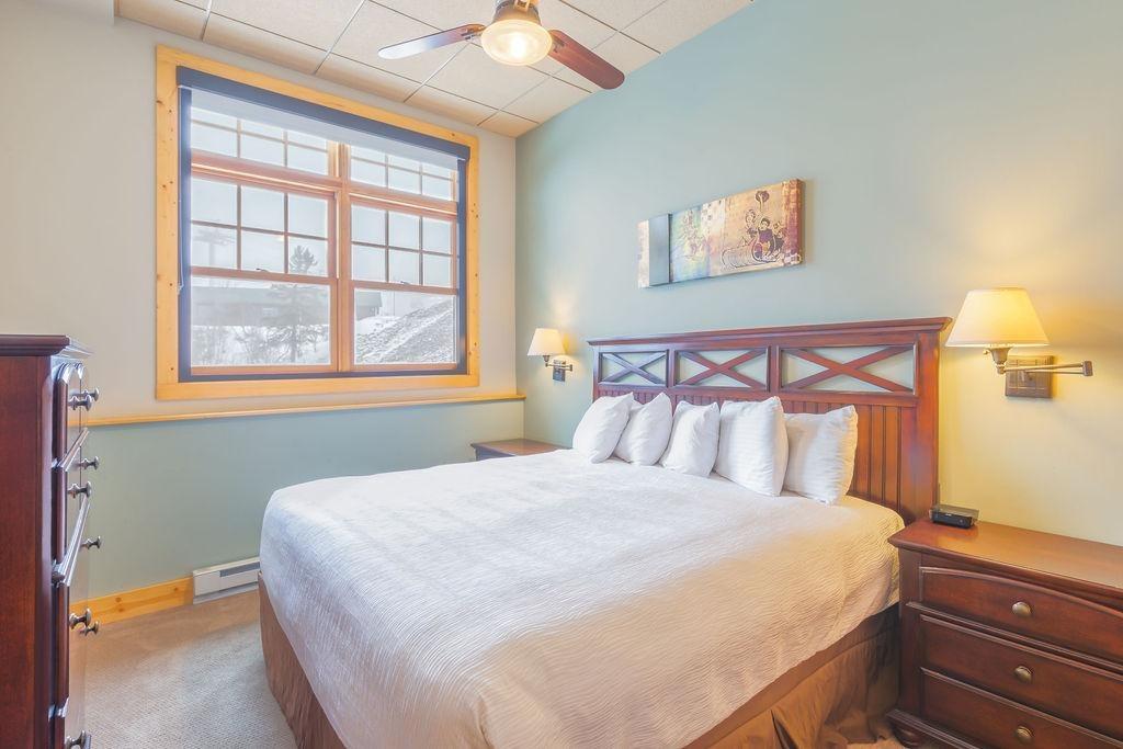 Cozy bedroom with a large bed, wooden furniture, and a window with soft lighting.