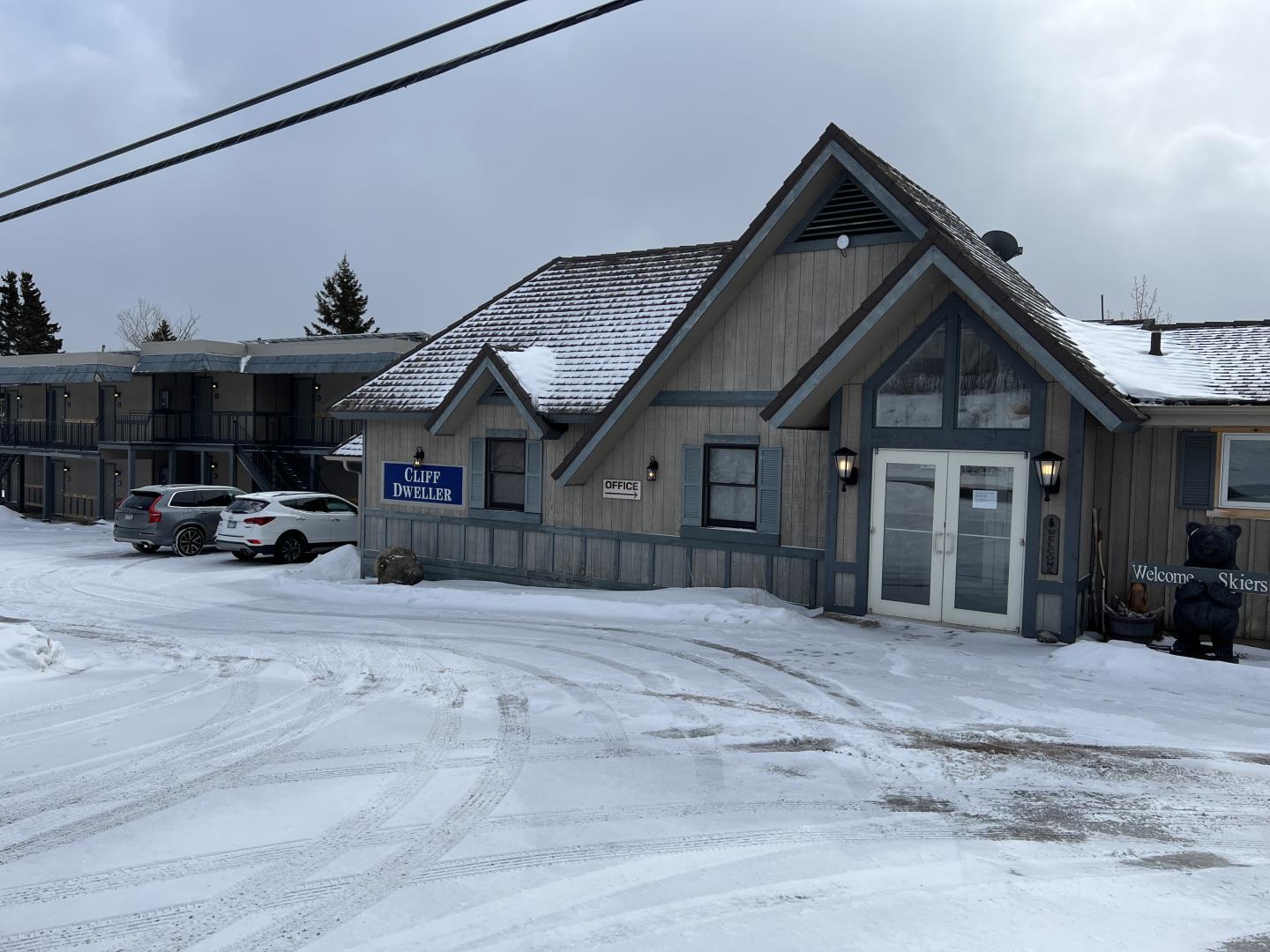 Snowy motel exterior with parked cars and overcast sky.