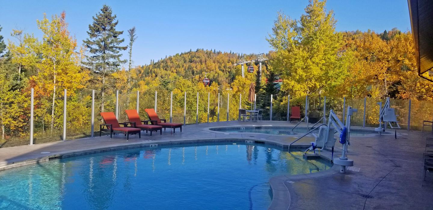 Poolside chairs with autumn trees and mountains in the background.