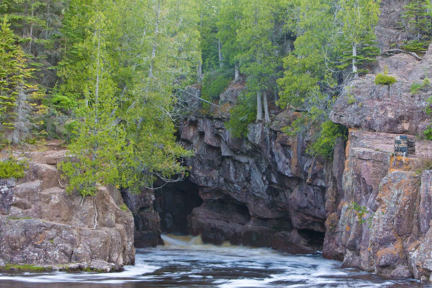 Rocky waterfall surrounded by lush green trees.