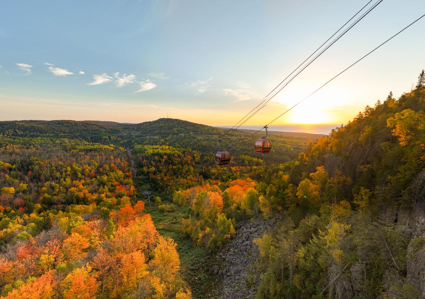 Cable cars over autumn forest at sunset.
