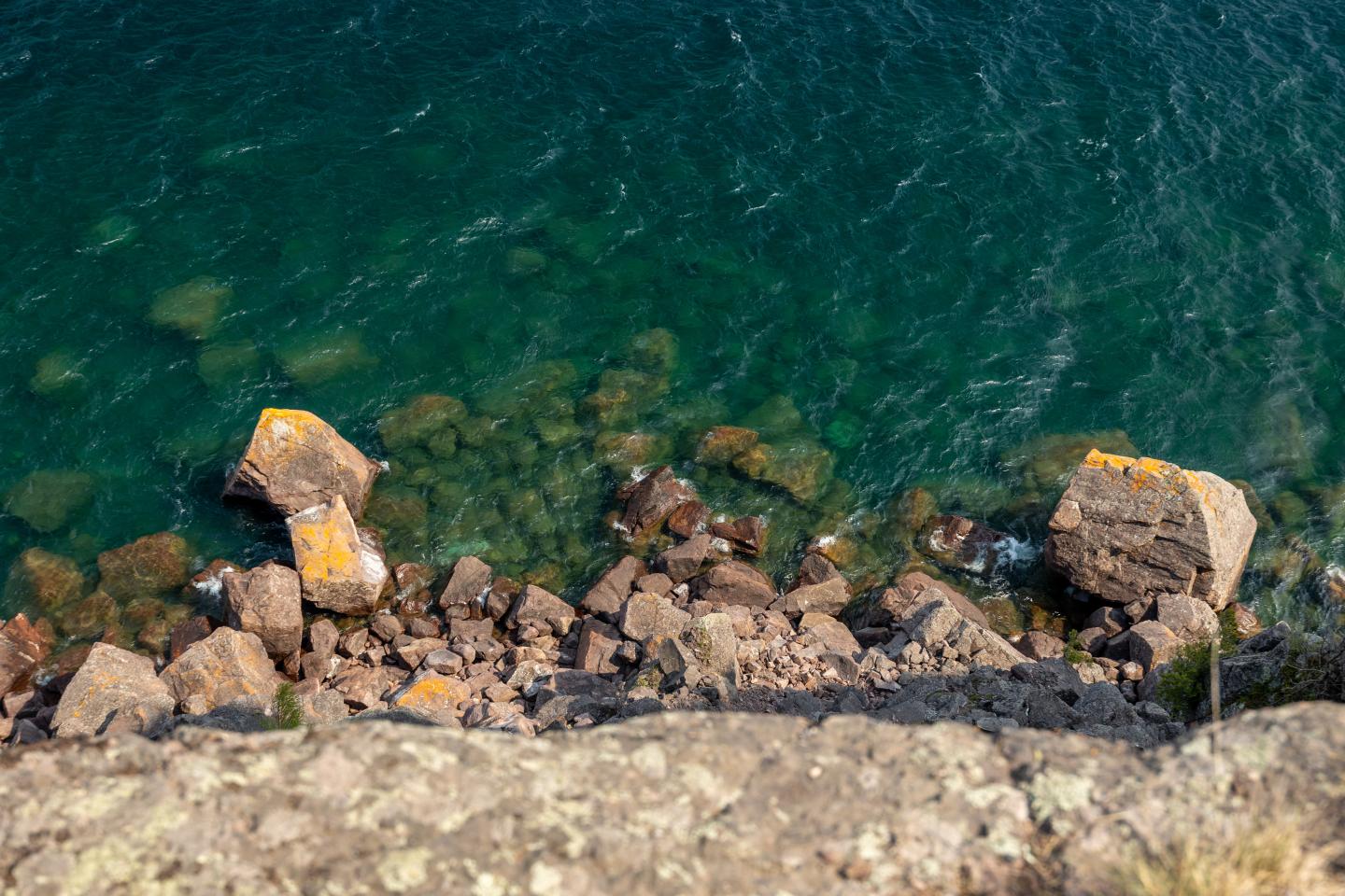 Cliffside view of rocks and turquoise sea below.
