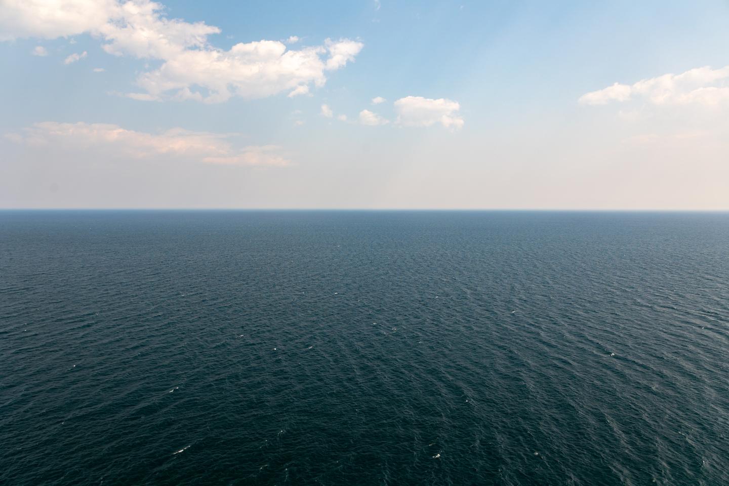 Calm lake view under a blue sky with scattered clouds.
