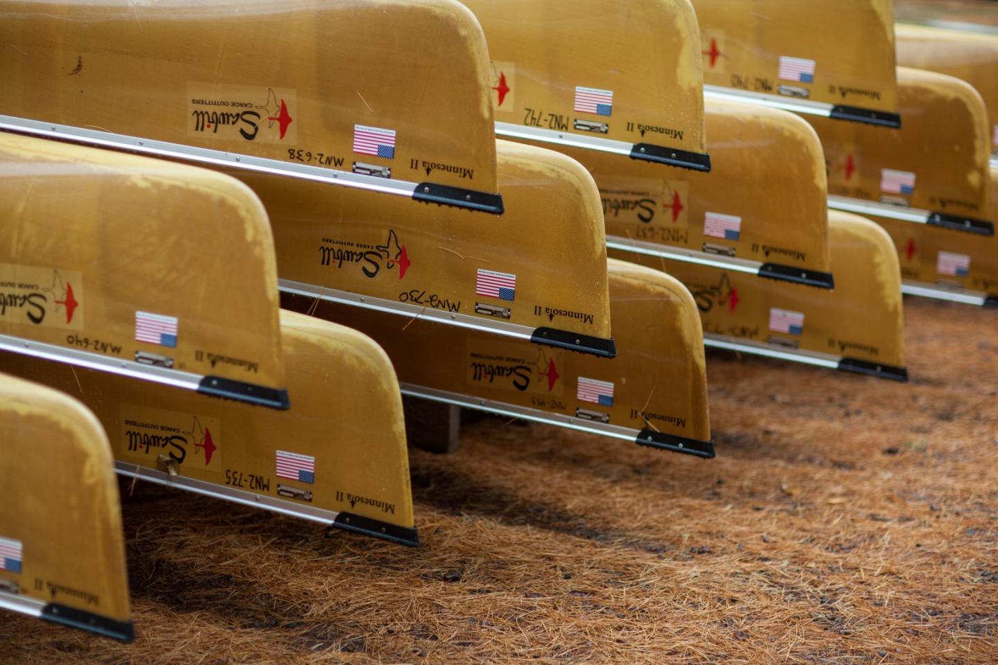 Yellow canoes lined up on a brown, textured surface.