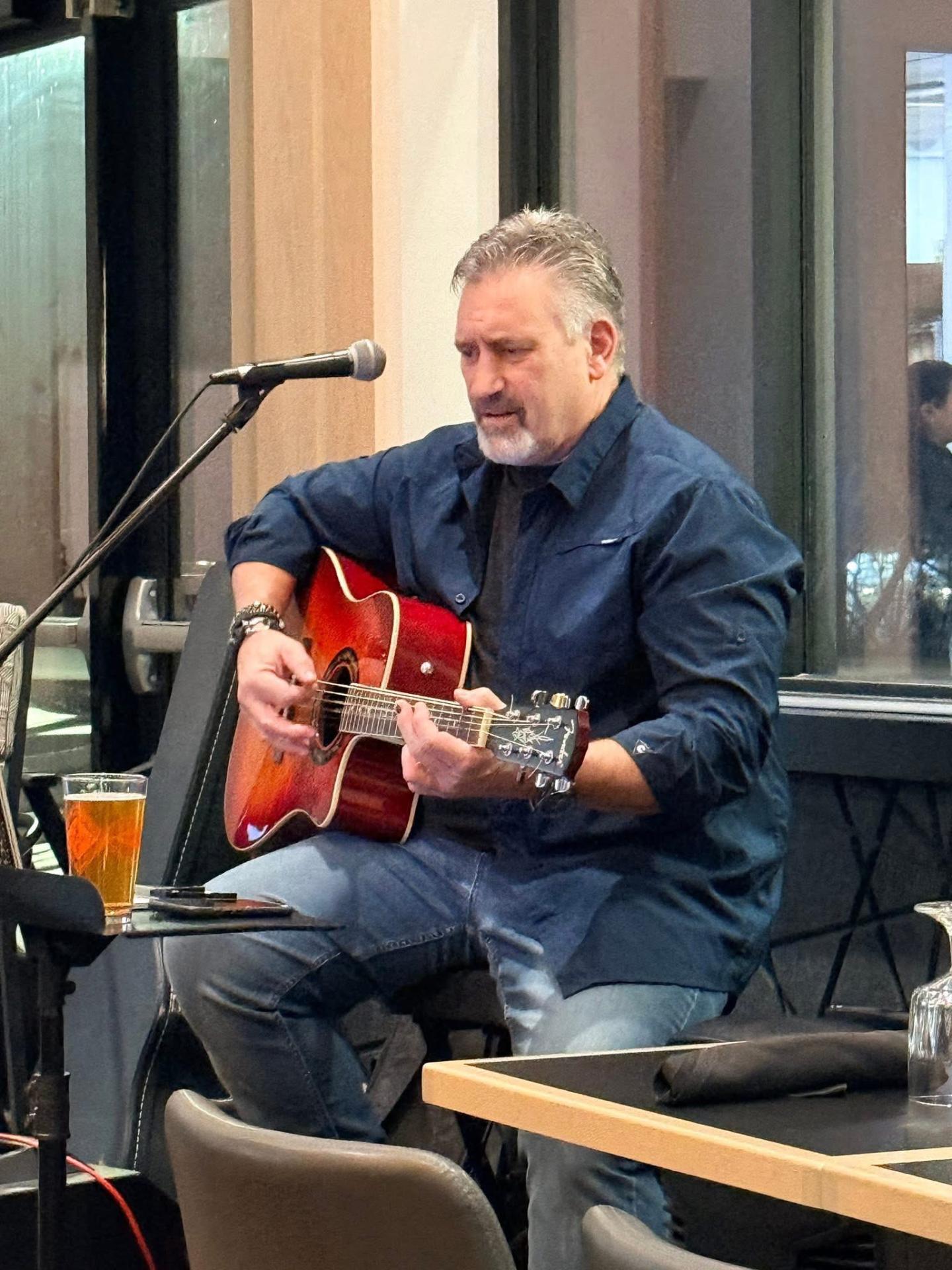 Man playing guitar and singing in a cozy indoor setting.