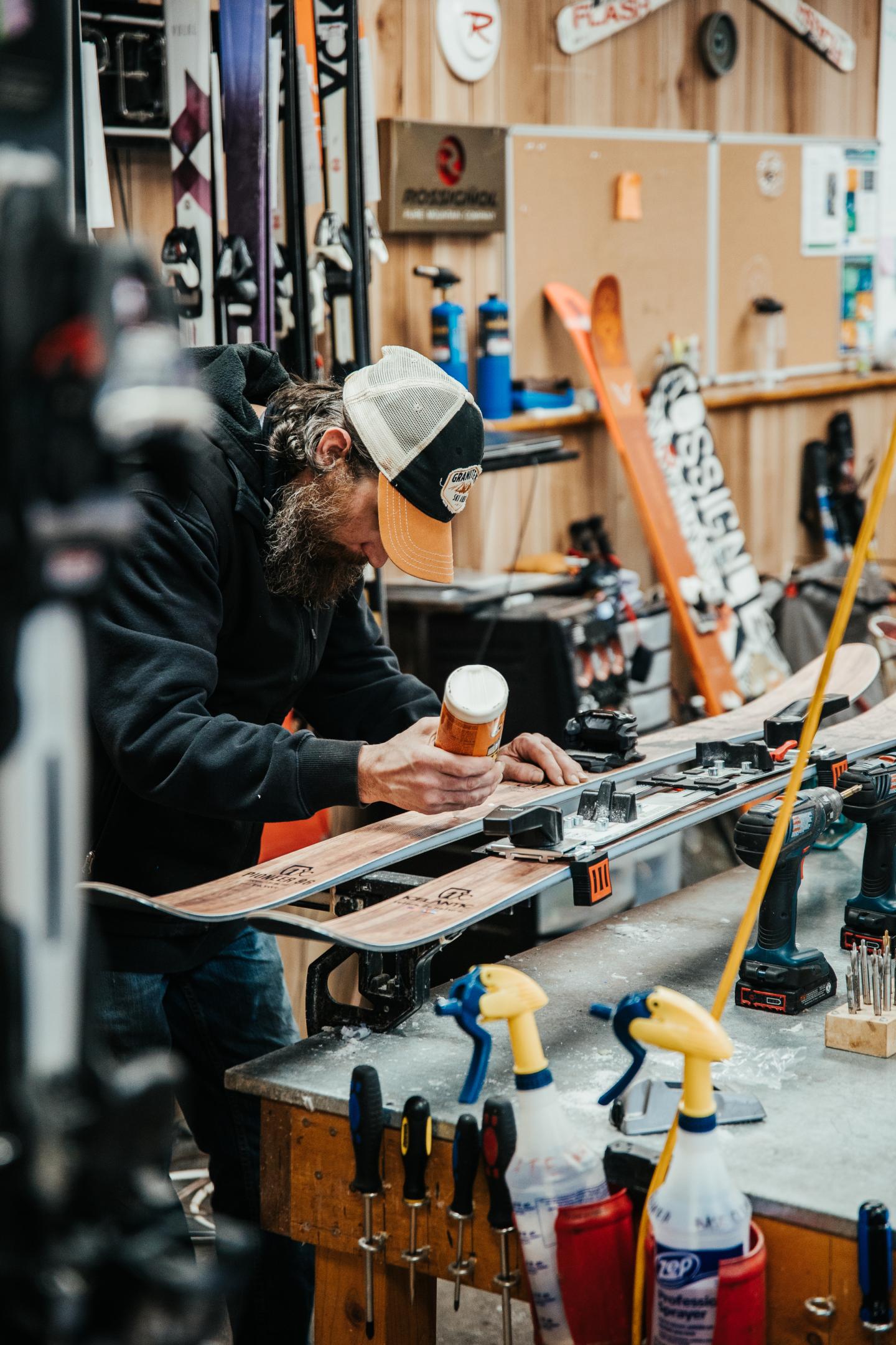 Ski technician tuning skis in a workshop.