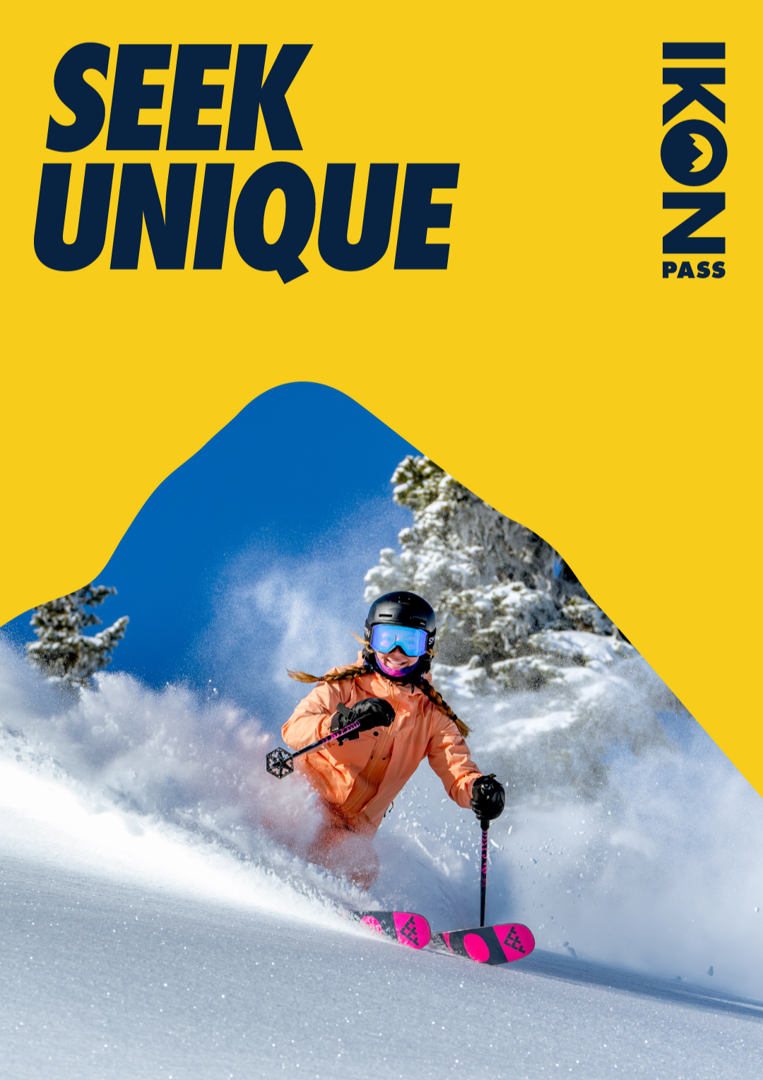 Skier in orange jacket on snowy slope, blue sky background.